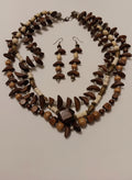Necklace and earrings with brown and beige beads on a light pink background
