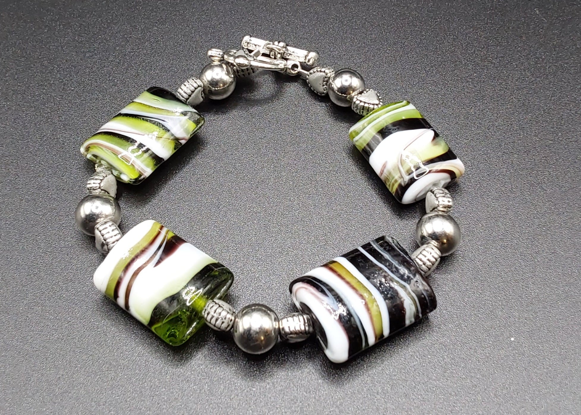 Marble Green Black White with Silver Clasp Bracelet striped beads on a black background